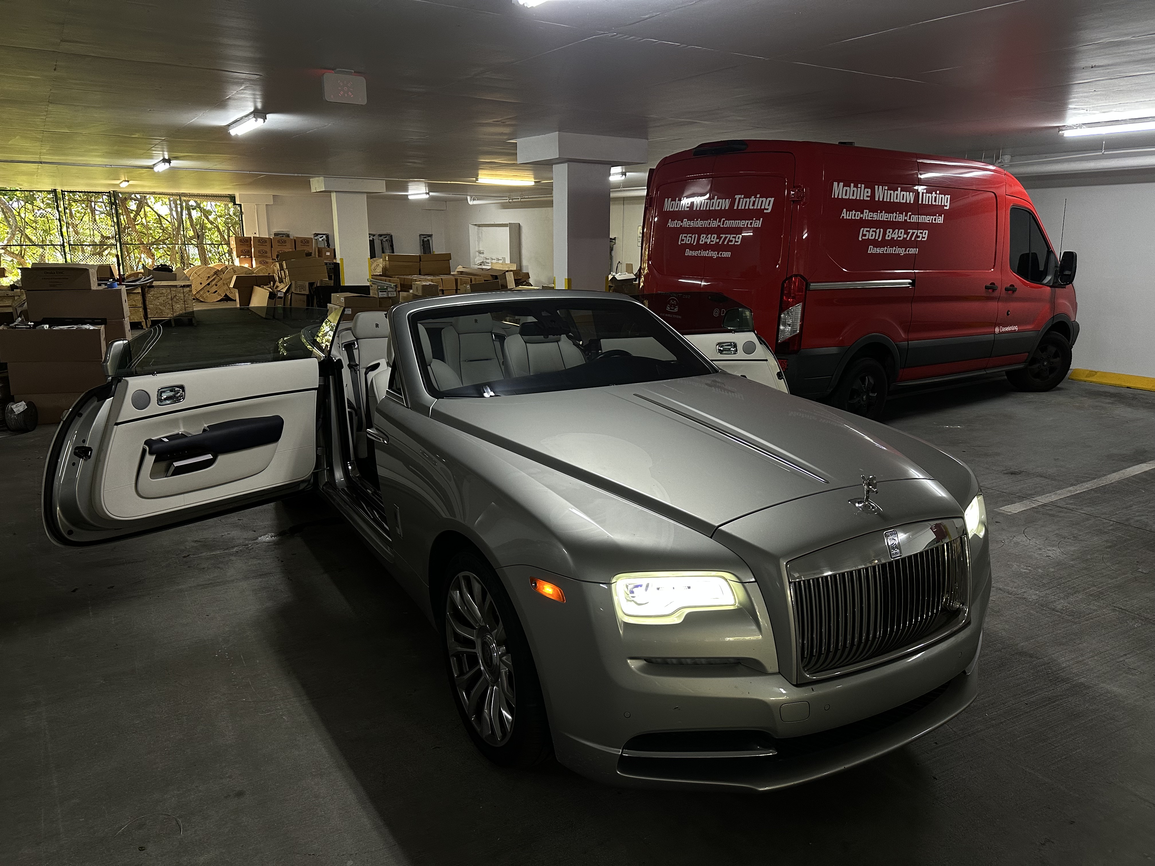 The alt text for the image is: "A Rolls-Royce and/or van with advertising vinyl, possibly in a warehouse".